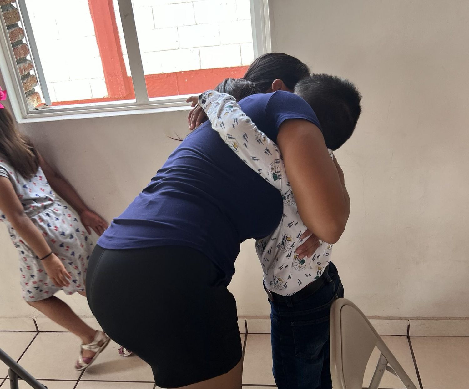 Elvia bent down, holding a boy in a full embrace inside a room at the children's home