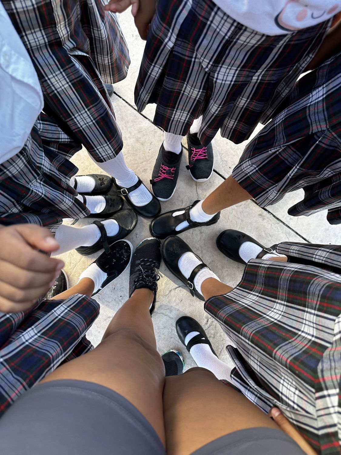School shoes gathered in a circle on a tiled courtyard floor
